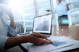 business documents on office table with smart phone and laptop computer and graph business with social network diagram and two colleagues discussing data in the background.jpeg